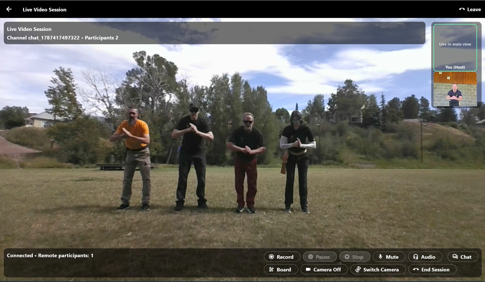 A live session on the desktop app: four students training on grass in the main view, the host's own camera beside it, with record, whiteboard, camera and end-session controls along the bottom